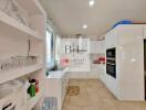 Modern kitchen with white cabinetry, marble backsplash, and built-in appliances