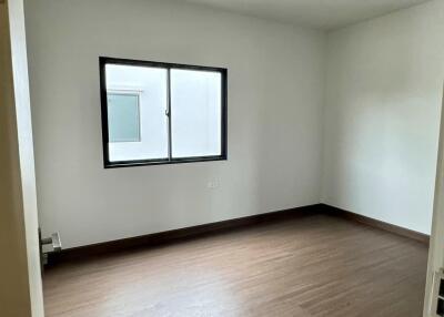 Empty bedroom with wooden flooring and a window