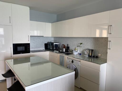 Modern kitchen with white cabinets, integrated appliances, and island