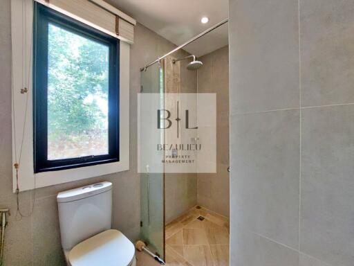 Modern bathroom with toilet, window, and glass-enclosed shower