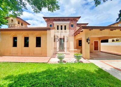 Exterior view of a large, Mediterranean-style house with well-maintained landscaping