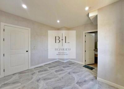 spacious empty bedroom with tile flooring and two doors