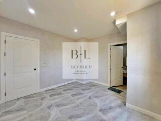 spacious empty bedroom with tile flooring and two doors