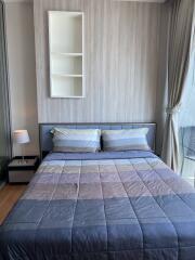 Modern bedroom with a double bed, bedside table, lamp, and bookshelf