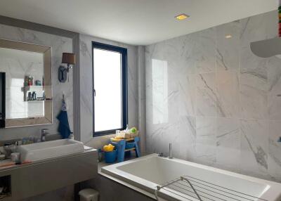 Modern bathroom with bathtub, large mirror, and window