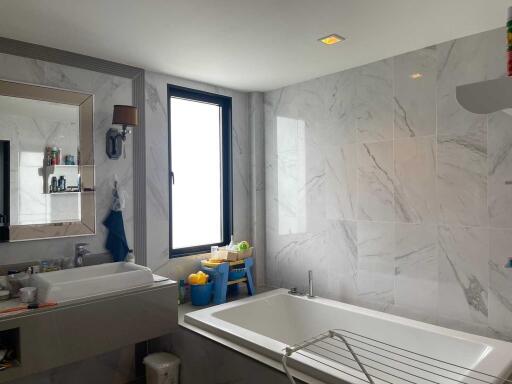 Modern bathroom with bathtub, large mirror, and window