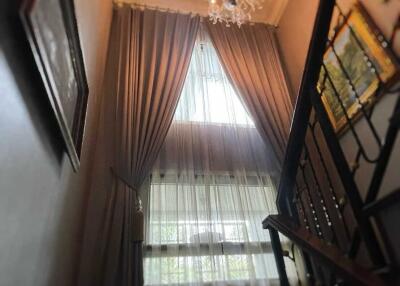 Staircase with chandelier and large window with drapes