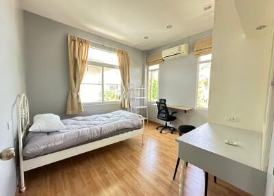 Modern, well-lit bedroom with a single bed, desk, and large window