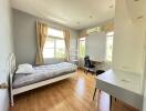 Modern, well-lit bedroom with a single bed, desk, and large window