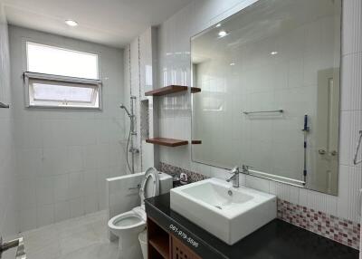 Modern bathroom with large mirror, sink, toilet, and shower area