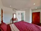 Bedroom with red bedding and wooden furniture