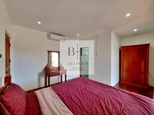 Bedroom with red bedding and wooden furniture