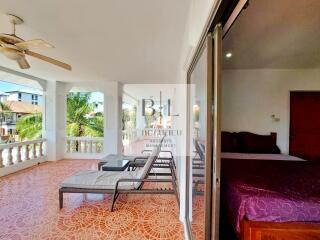 Spacious balcony with lounge chairs and ceiling fan, adjacent to bedroom