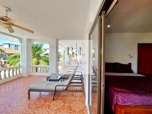 Spacious balcony with lounge chairs and ceiling fan, adjacent to bedroom