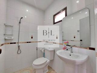 Modern bathroom with white tiles, a toilet, a sink, a shower area, and a mirror