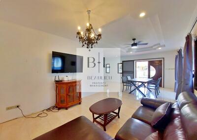 Spacious living room with leather seating, wall-mounted TV, and dining area