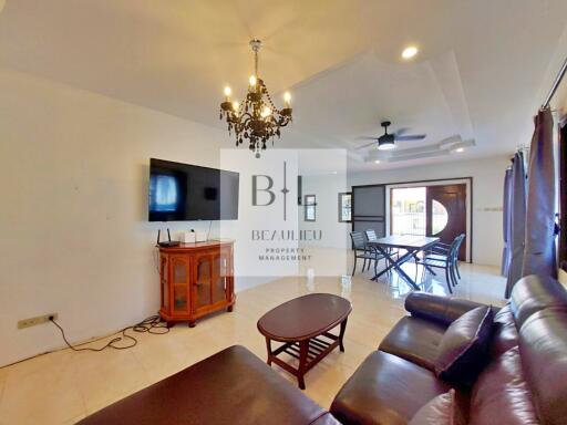 Spacious living room with leather seating, wall-mounted TV, and dining area