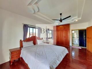 Spacious bedroom with bed, nightstand, and wooden wardrobe