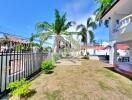 Spacious garden area with palm trees and a gated entrance