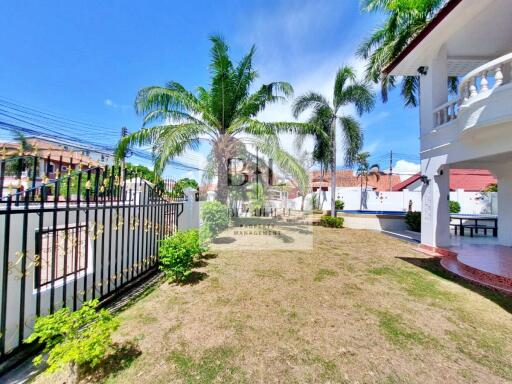 Spacious garden area with palm trees and a gated entrance