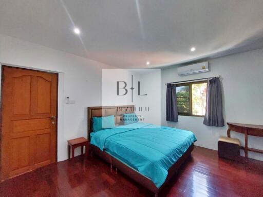 Bedroom with wooden floor, double bed, desk, and window with AC