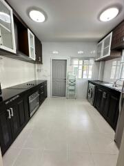 Modern kitchen with black and white cabinets, built-in appliances, and tiled flooring