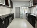 Modern kitchen with black and white cabinets, built-in appliances, and tiled flooring