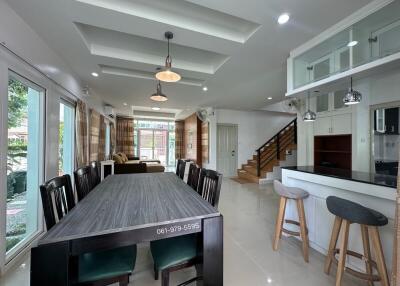 Modern open-plan living area with dining table, kitchen island, and staircase