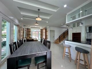 Modern open-plan living area with dining table, kitchen island, and staircase