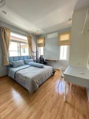 Modern bedroom with wooden floor, grey bedding, work desk and chair by windows