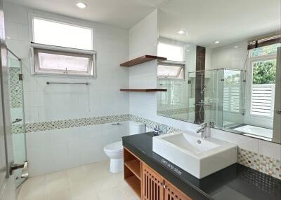 Modern bathroom with large mirror, vanity sink, bathtub, and natural light