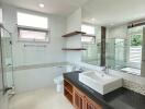 Modern bathroom with large mirror, vanity sink, bathtub, and natural light