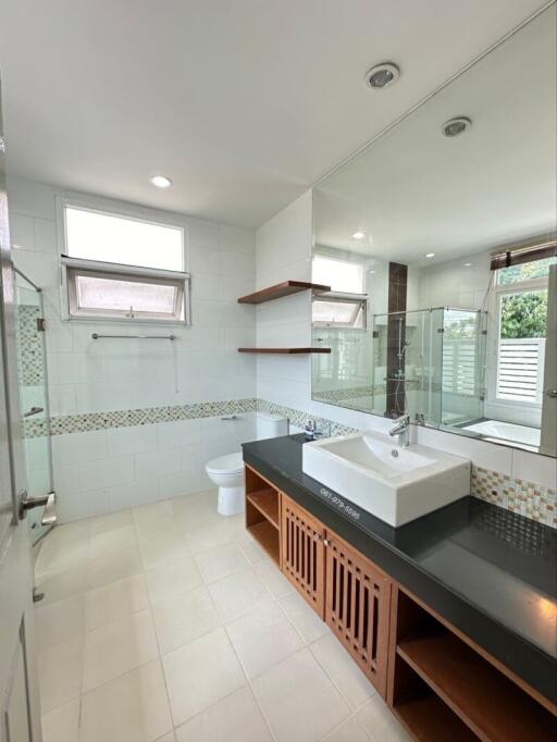 Modern bathroom with large mirror, vanity sink, bathtub, and natural light