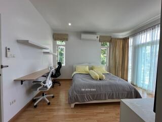 Bright bedroom with bed, desk, and large windows