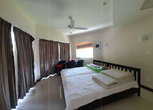 A well-lit bedroom with double bed, cozy seating area, and large windows