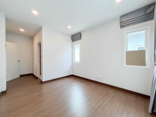 Spacious unfurnished bedroom with wooden floors and bright lighting