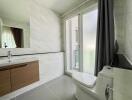 Modern bathroom with large mirror, vanity, and toilet