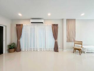 Minimalist living room with curtains, air conditioner, and a chair