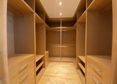 Spacious walk-in closet with built-in wooden shelves and drawers
