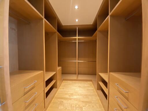 Spacious walk-in closet with built-in wooden shelves and drawers