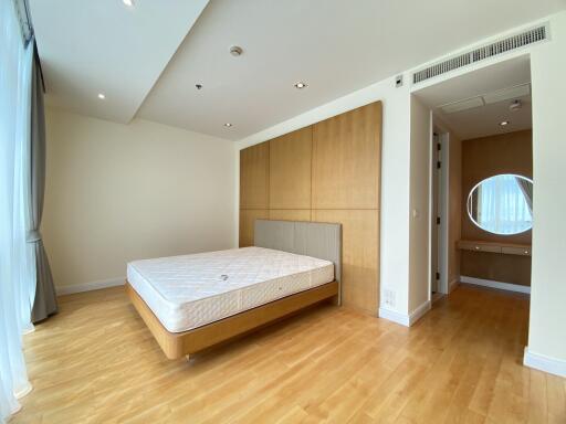 spacious bedroom with wood flooring and large window