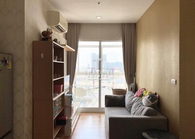 Cozy living room with a sofa, storage shelves, and large window.