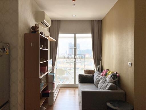 Cozy living room with a sofa, storage shelves, and large window.