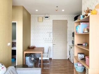 A living area with a view of the dining table, shelves, and washing machine.