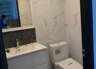 Modern bathroom with white tiled walls, toilet, and sink