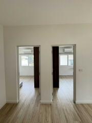 Two-door view into bedrooms with wooden flooring, large windows, and white walls