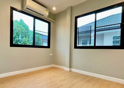 Empty bedroom with two large windows and air conditioning unit