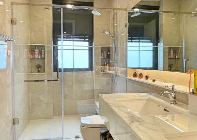 well-lit modern bathroom with glass shower enclosure and large mirror