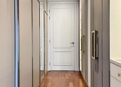 A well-lit and spacious walk-in closet with ample storage and wooden flooring