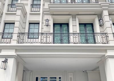 Front view of a residential building with white exterior, balconies, and large windows